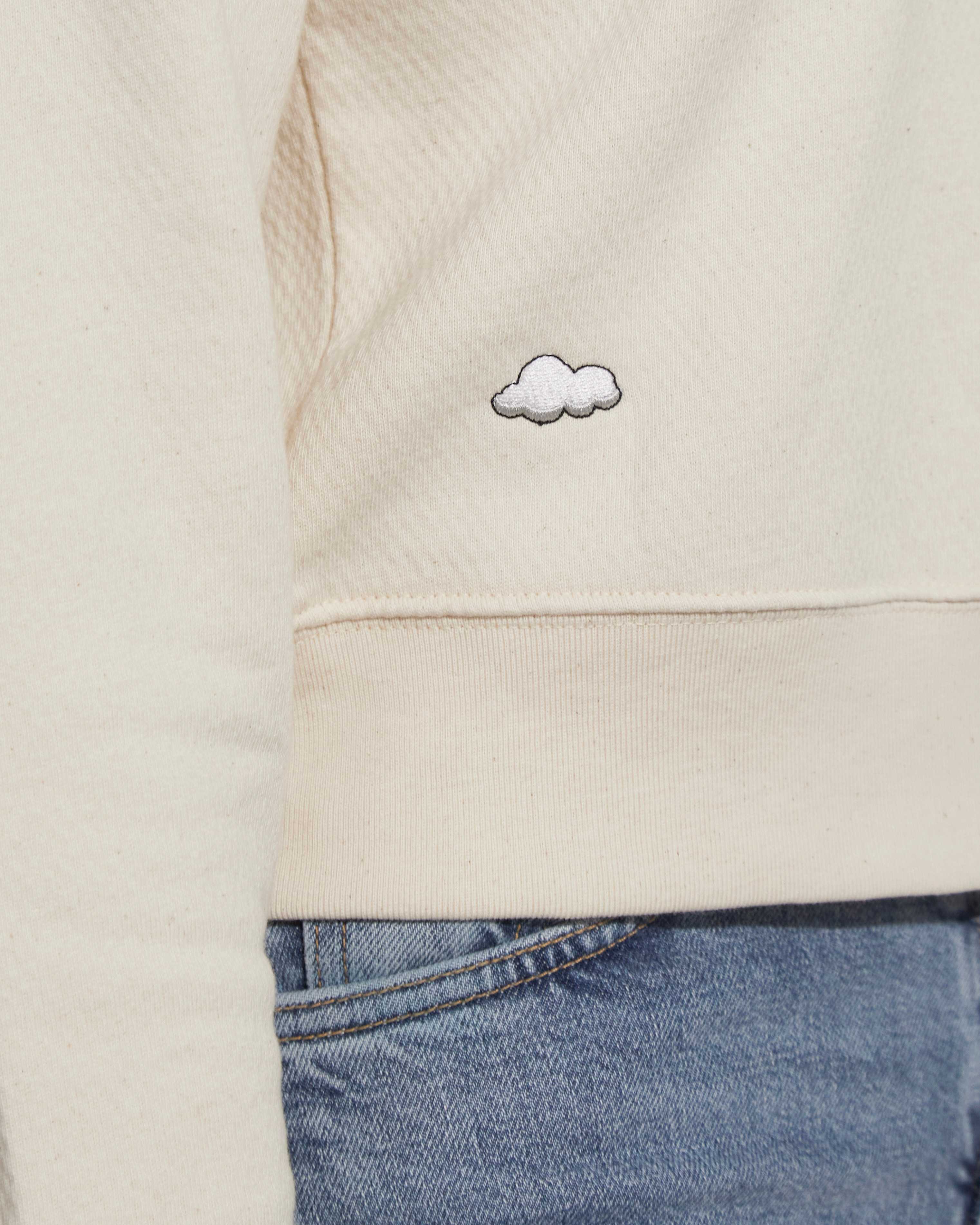 Closeup of a cloud embroidered on a cream ingmarson top and blue levis jeans 