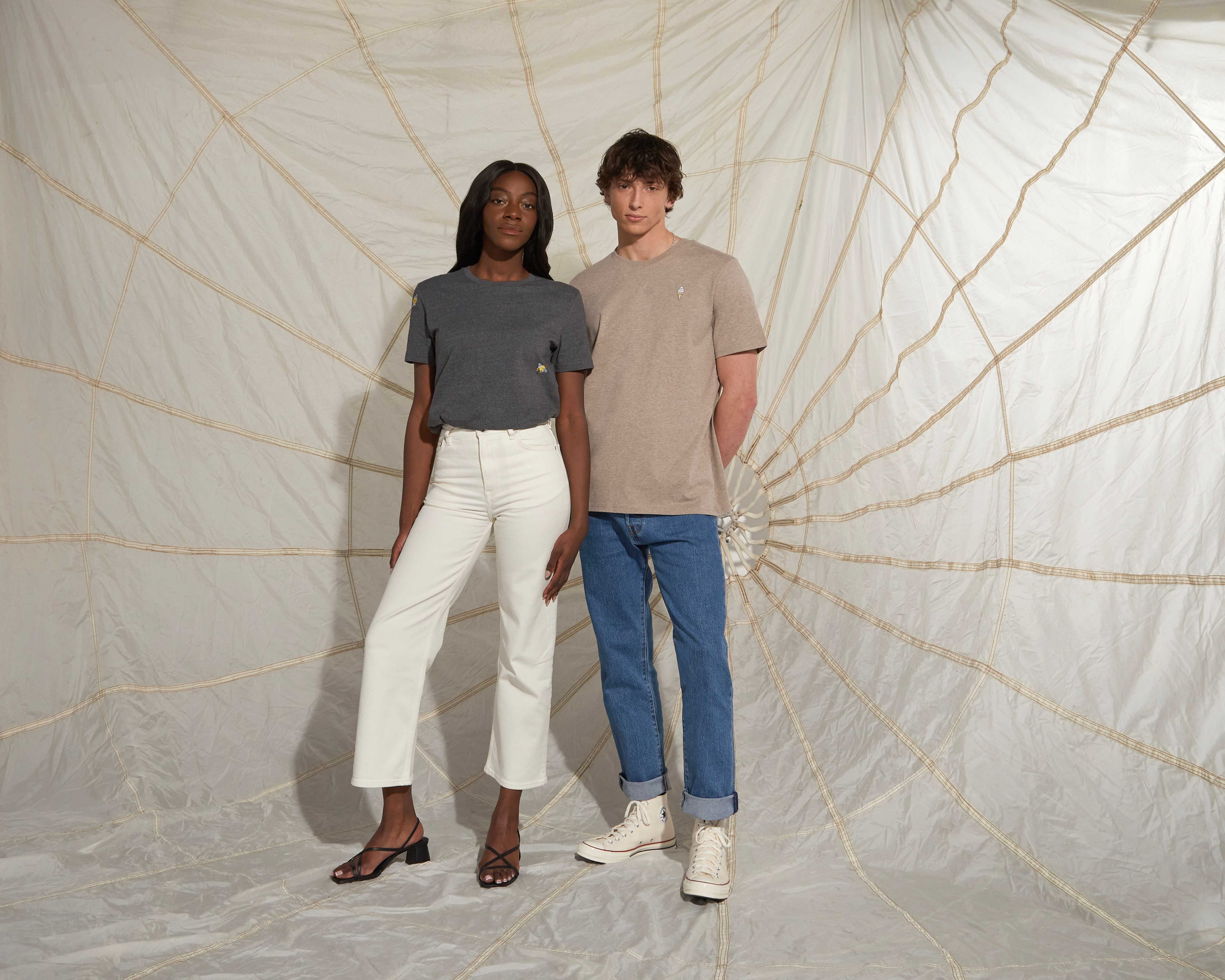Couple standing infront of a parashute wearing embroideared tshirts and levis jeans and converse shoes
